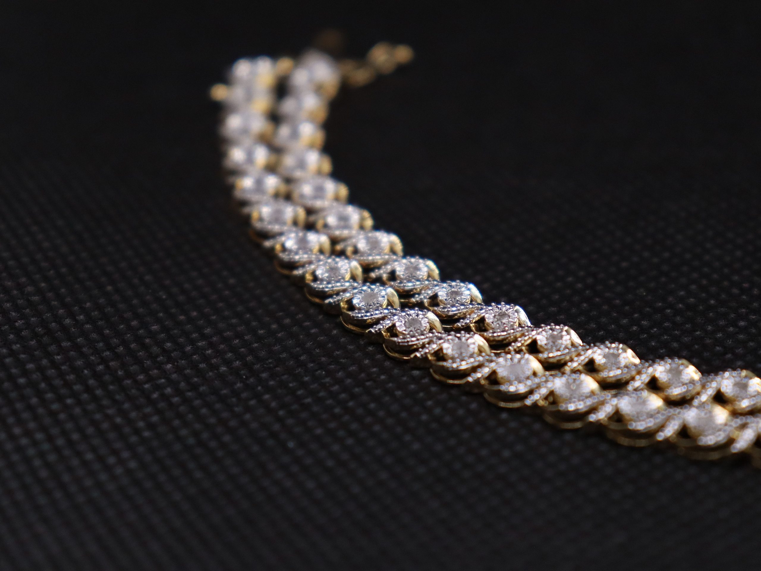 A closeup shot of a Diamond Tennis Bracelet on a black surface