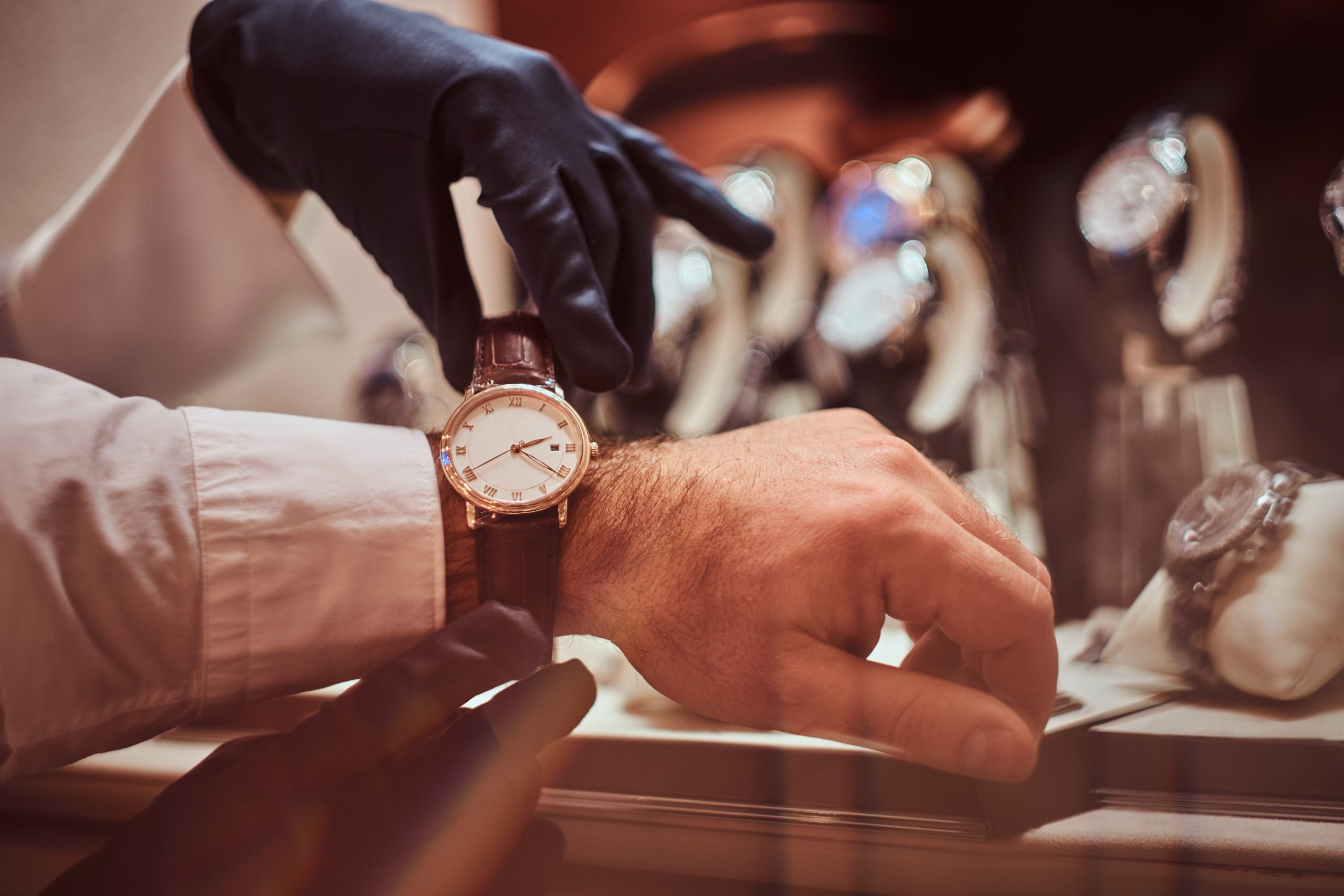 Close-up hands. Assistant helps the client to try on exclusive men's watches.
