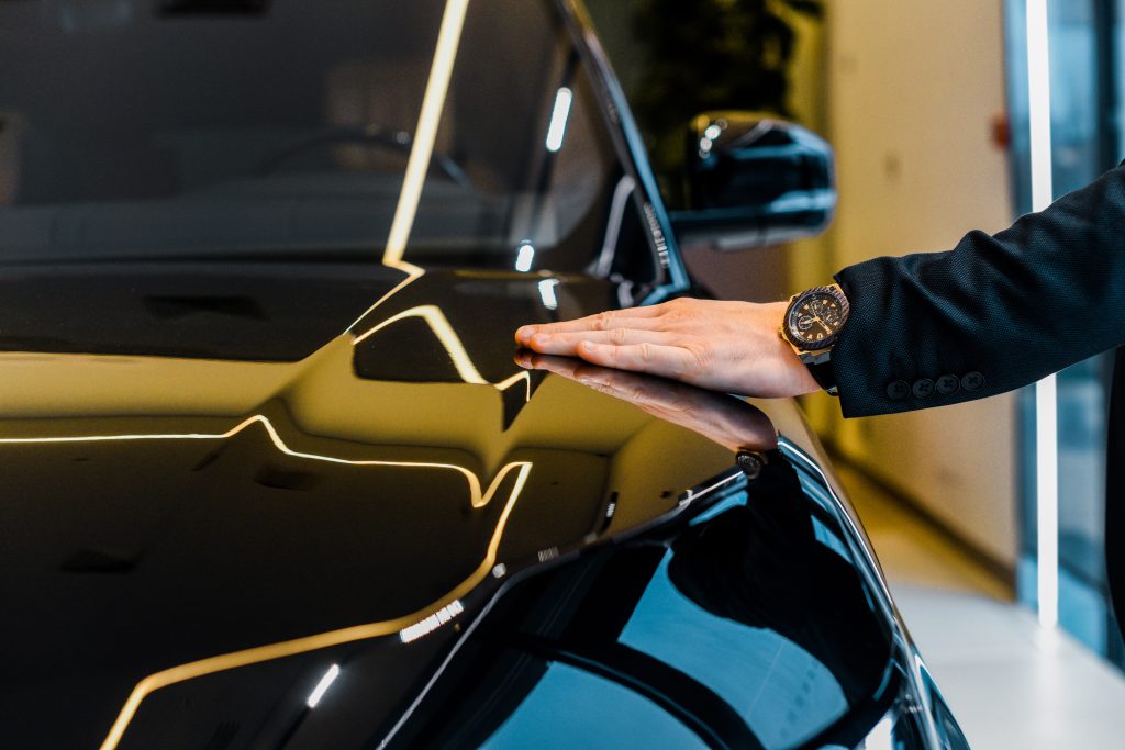 cropped image of businessman with luxury watch choosing automobile in dealership salon