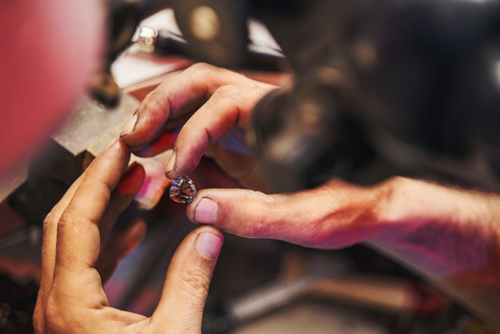 Jeweler is holding cut diamond between fingers