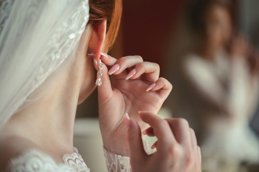 Wedding earrings on a woman's hand, she takes earrings, bride fees, morning bride, white dress